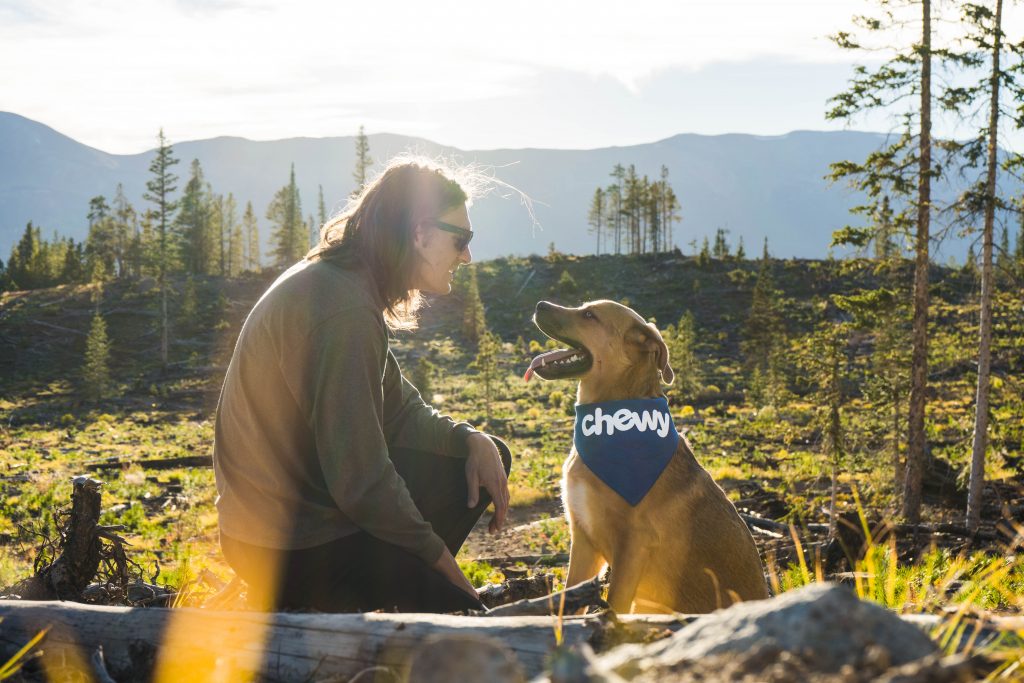 Happy dog and happy owner. Dog is wearing bandana which says "chewy".